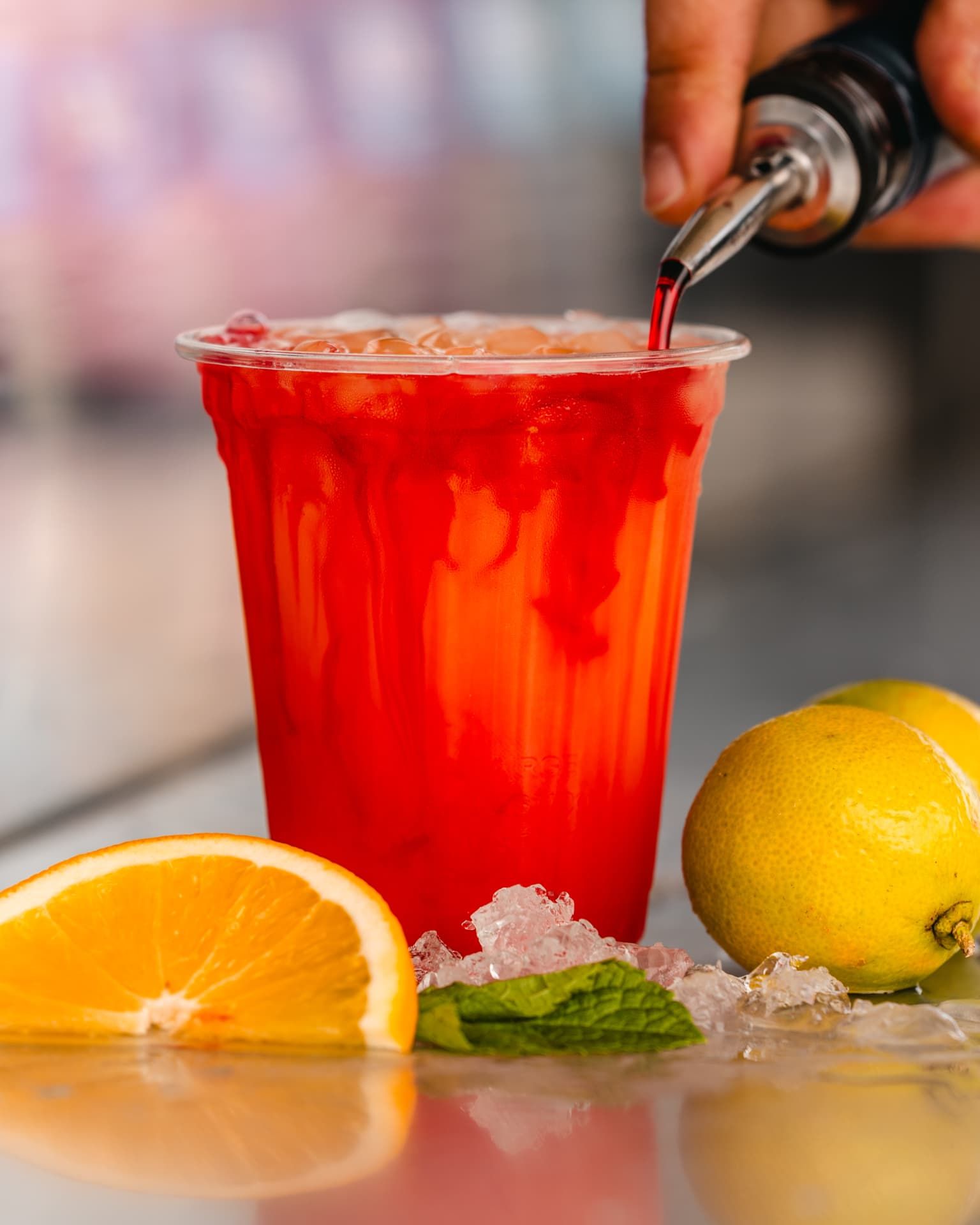 Sirup wird in einen roten Cocktail auf Crushed Ice gegossen