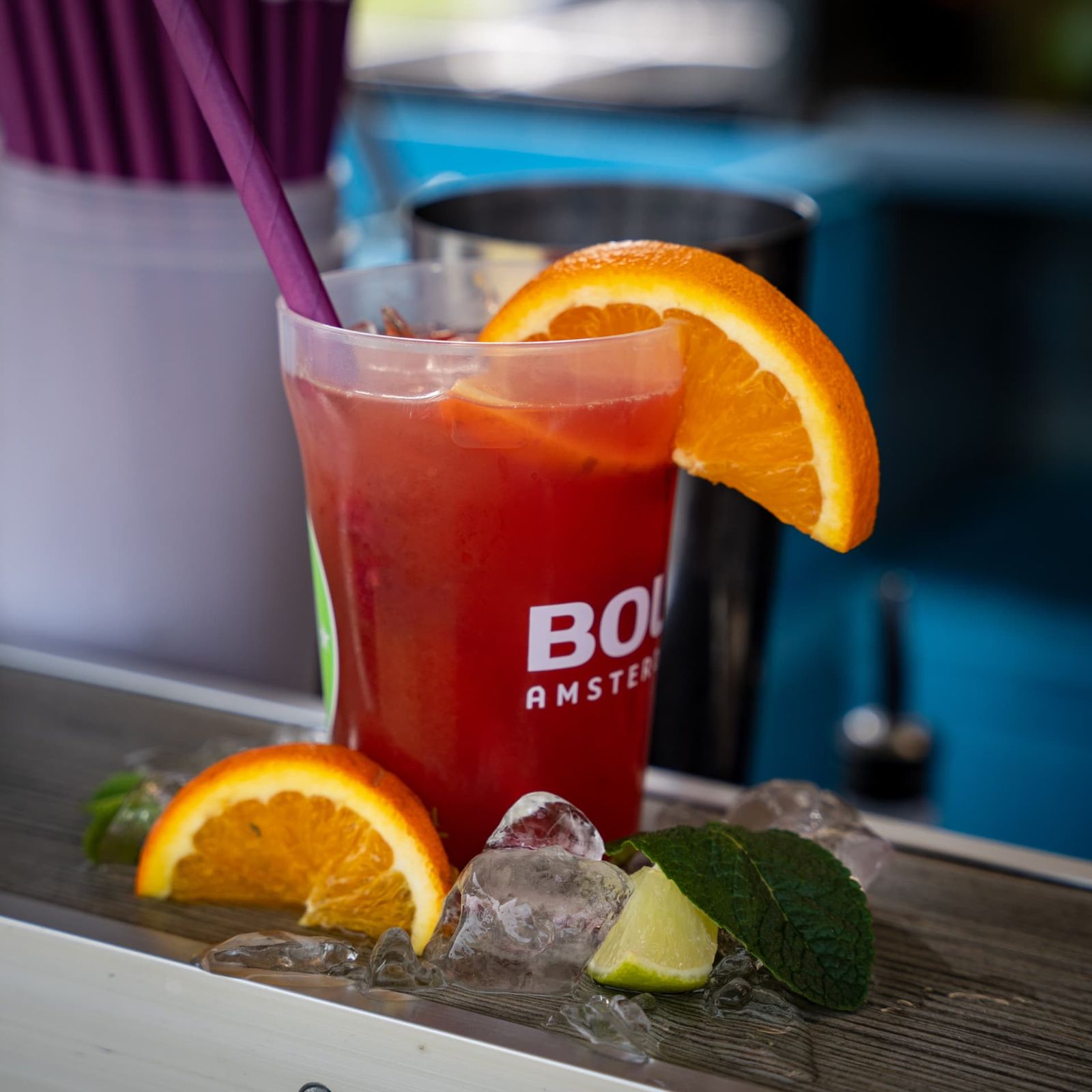 Roter Cocktail mit Orangenscheibe, Minze und Limette