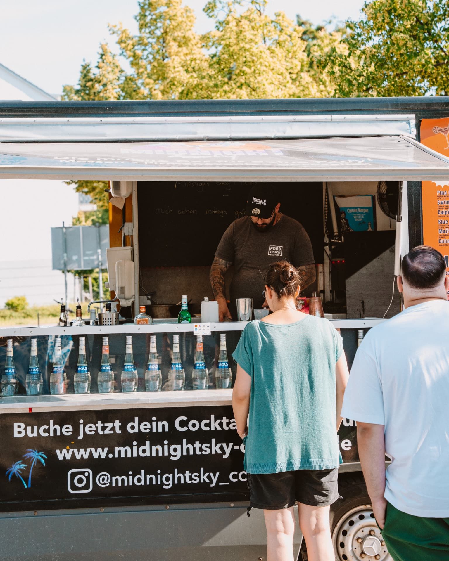 Midnight Sky Cocktailtruck mit Menütafel, im Inneren mixt der Barkeeper Cocktails