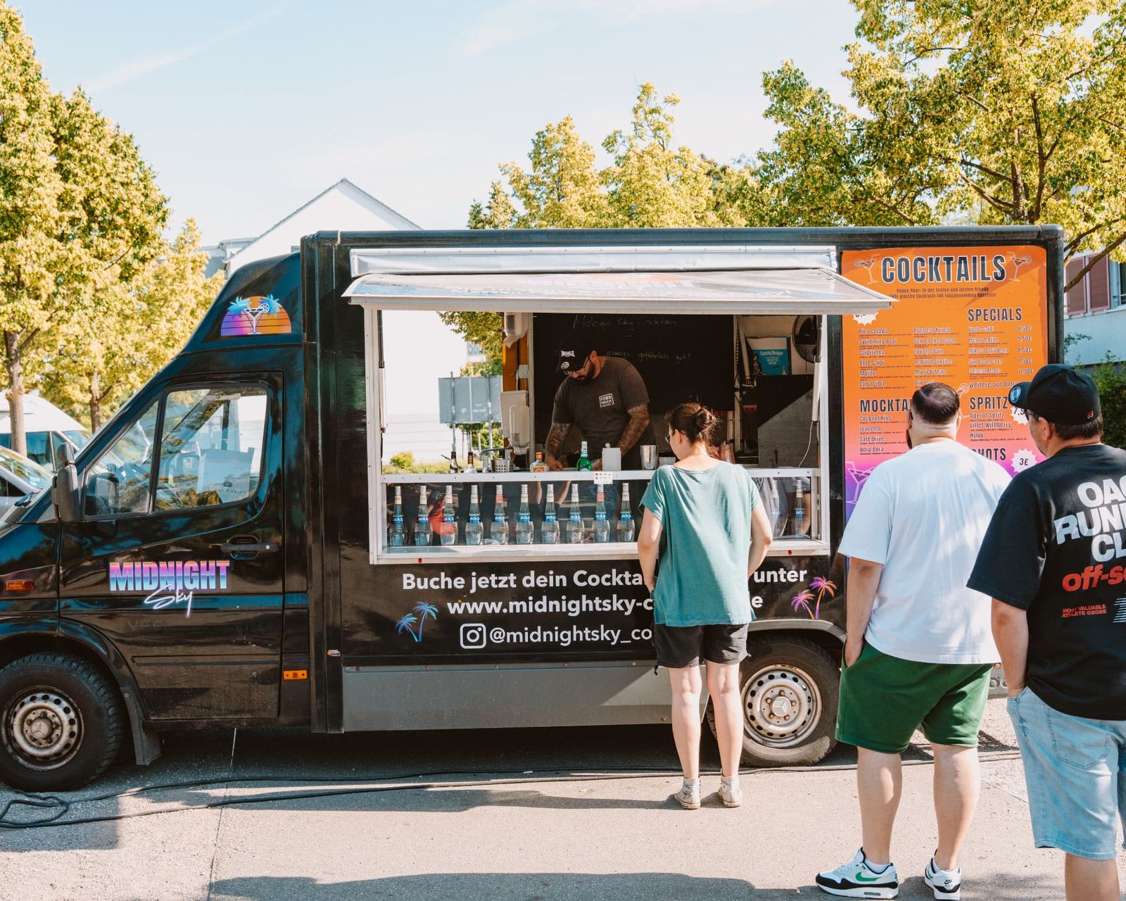 Der schwarze Midnight Sky Cocktailtruck auf einem Open-Air-Event mit wartenden Gästen